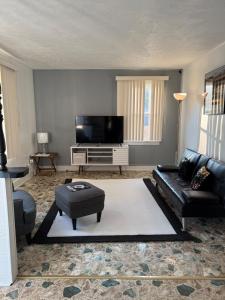a living room with a black leather couch and a flat screen tv at Master Bedroom with Attached SunRoom and Attached Patio in Richmond