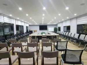 a large room with chairs and tables and a screen at City Comfort Inn Nanning International Exhibition Jinhu Plaza in Nanning