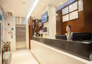 a woman sitting at a counter with a laptop at City Comfort Inn Nanning Chaoyang Square Zhongshan Road Food Street in Nanning