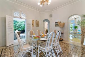 a dining room with a glass table and white chairs at Casa Damiana, Colonial Charm with Private Pool in Mérida