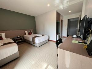 a hotel room with two beds and a flat screen tv at Baan Nan B&B Hotel in Nan