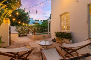 a patio with chairs and a table and lights at Casa Damiana, Colonial Charm with Private Pool in Mérida