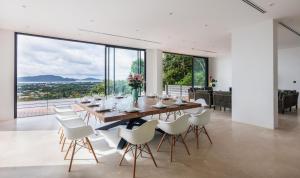 a dining room with a long wooden table and white chairs at Stunning Views - Villa Maan Ingfah (VMI1) in Ban Na Kok