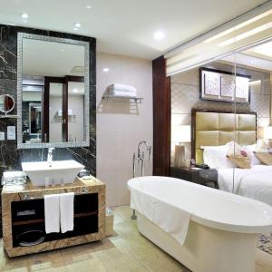 a bathroom with a tub and a bed and a large mirror at Dahe Jinjiang Hotel in Zhengzhou