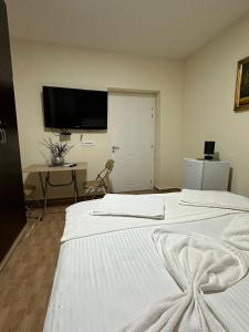 a bedroom with two beds and a television on the wall at Gledys House in Krujë
