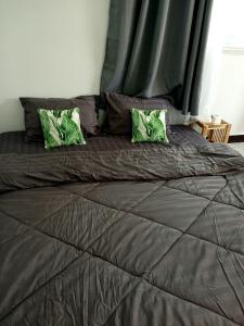 un grand lit avec deux oreillers verts dessus dans l'établissement 119 Boutique Natural Wellness Chiang Mai, à Chiang Mai