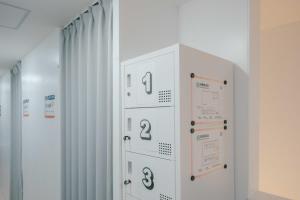 a white locker with numbers on it in a room at TRANSIT HOSTEL Cafe and Bar in Izumi-Sano