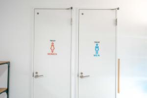 a row of white doors with signs on them at TRANSIT HOSTEL Cafe and Bar in Izumi-Sano +9 photos