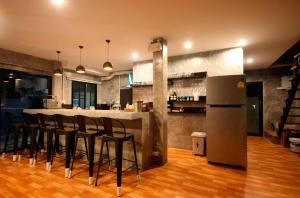 a kitchen with a bar with black stools and a refrigerator at Aonang Lodge - SHA in Ao Nang Beach