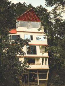 a tall white house with a red roof at Dzukou Lodge in Kohīma