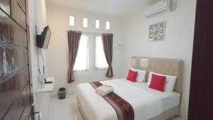 a bedroom with a white bed with red pillows at House of A Syariah Kedamaian in Bandar Lampung