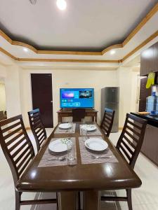 a dining room table with chairs and a television at TPRC Residences in Baguio +2 photos