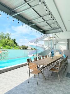 a patio with a wooden table and chairs and a pool at The Ocean Pool Villa HuaHin in Hua Hin
