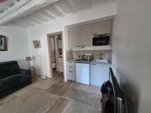 a kitchen with white cabinets and a black couch at Studio au coeur d'un Mas in Montpellier