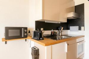 a kitchen counter with a microwave and a sink at Vue imprenable sur les Alpes et Parking privé gratuit in Crans-Montana