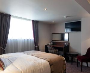 a hotel room with a bed and a desk at The White Hart Hotel Wetherspoon in Okehampton