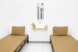 two beds in a room with a window at Hotel Griya Kopi in Pekalongan