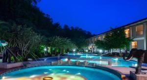 una piscina en un hotel por la noche en River Kwai Village Hotel, en Ban Kaeng Raboet