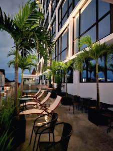 a patio with chairs and palm trees in front of a building at The Jogja Malioboro Hotel and Conference Center in Yogyakarta
