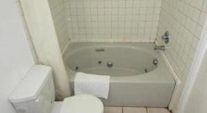 a bathroom with a white tub and a toilet at Coast Motel in Signal Hill +14 photos