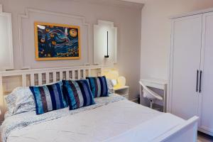 a white bed with blue pillows in a bedroom at Nettuno ValQuirico in Santeagueda