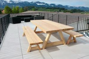 a wooden picnic table and bench on a balcony at Fuchs at home in Kaltbrunn