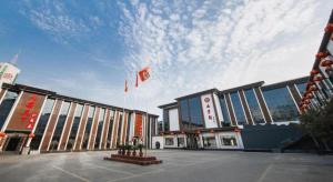 ZhongyuanyoutianにあるGreenTree Inn Puyang Ruifengyuan Business Hotelの旗の目の前の大きな建物