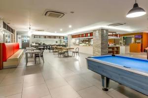 a pool table in a room with tables and chairs at Royal Bay Hotel Makassar in Makassar