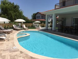 a swimming pool with chairs and umbrellas next to a house at Crescent Twins -White Villa in Dalyan