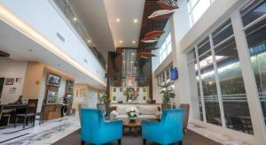 a lobby with blue chairs and a couch and a table at Java Lotus Hotel Jember in Jember