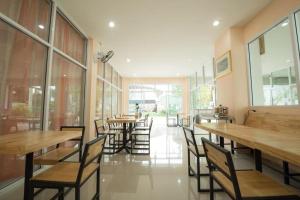 a restaurant with wooden tables and chairs and windows at Bees Smile Hotel in Ban Fang Min +86 photos