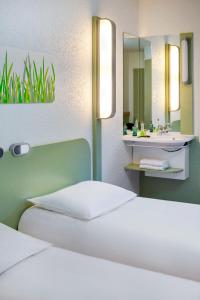 a bedroom with a bed and a sink and a mirror at ibis Budget Courbevoie Paris La Défense in Courbevoie