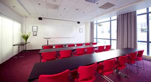 una sala de conferencias con una mesa larga y sillas rojas en Clarion Collection Hotel Grand Olav, en Trondheim