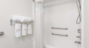 une salle de bain avec douche et serviettes blanches dans l'établissement Jesup Inn & Suites, à Jesup