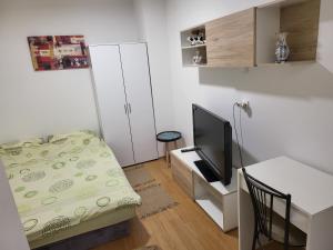 een kleine kamer met een bed en een tv bij Apartman u centru Prnjavor in Prnjavor