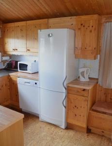 a white refrigerator in a kitchen with wooden cabinets at Ol-jons By in Hallen