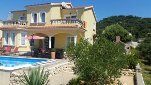 a large yellow house with a swimming pool in front of it at Villa Rosana in Rab +12 photos
