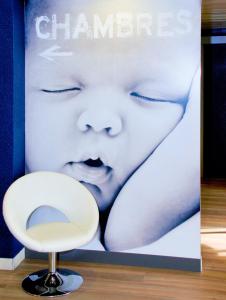 a poster of a baby and a white chair at ibis Budget Courbevoie Paris La Défense in Courbevoie