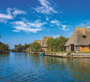 a group of buildings on the water next to a river at La perla di Maria in Grado