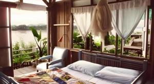 une chambre avec un lit et une grande fenêtre dans l'établissement Baan ChanKhiang at ChiangKhan, à Chiang Khan