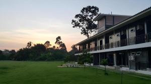 a building with a large field in front of it at Loft Village in Ban Khlong Kathon