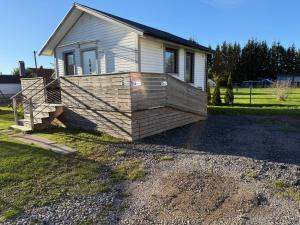 a small house with a wooden deck in the yard at Jönåker Cottage & Sauna in Jönåker +3 photos