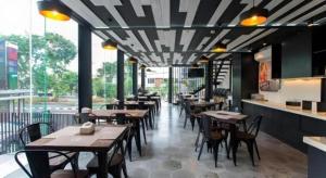 a restaurant with tables and chairs in a room at Zoom Dharmahusada Hotel in Surabaya