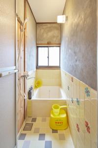 ein Badezimmer mit einer Badewanne und einem gelben Stuhl in der Unterkunft Retoro Meieki 2號室 in Nagoya
