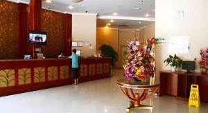 a man standing at a counter in a hotel lobby at GreenTree Inn Kunshan Shimao Plaza Business Hotel in Penglang