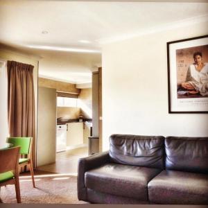 a living room with a leather couch and a kitchen at Forrest Hotel & Apartments in Canberra