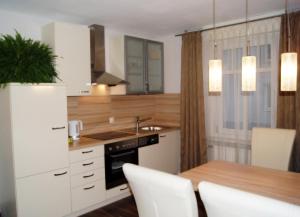 a kitchen with white cabinets and a table with white chairs at Haus Rosegger in Feldkirch