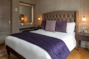 a bedroom with a large bed with purple pillows at La Clef Louvre Paris by The Crest Collection in Paris