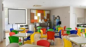 Un aula con mesas y sillas de colores en una cafetería. en Hotel New Coklat, en Surabaya 28 fotos más