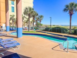 a swimming pool in a hotel with chairs and palm trees at Verandas 602 in North Myrtle Beach